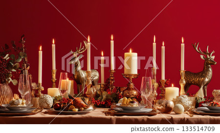 Festive holiday table setting with lit candles, golden reindeer figurines, and elegant dinnerware on red background 133514709