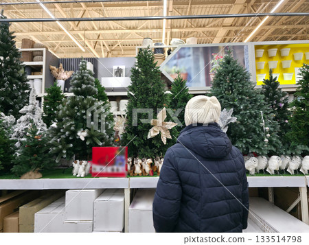 Woman Browsing Artificial Christmas Trees in Store Woman Browsing Artificial Christmas Trees in Store 133514798