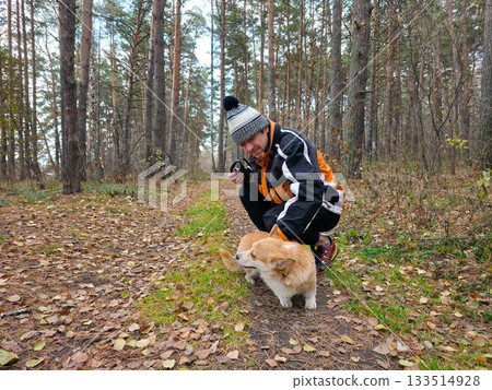 Man Playing with Corgi Dog in Autumn Forest 133514928