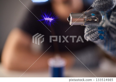 Hands test plasma, Detailed image of electrical discharge testing process, Precision testing of purple plasma arc by technician wearing gloves with detailed equipment 133514985