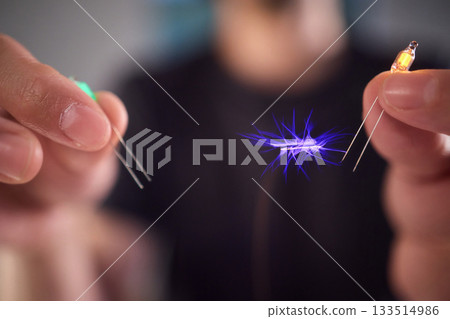 Hands manipulating metal spheres generate vibrant electrical plasma display, Laboratory scene showcasing coil discharging luminous sparks with scientific precision Hands manipulating metal spheres generate vibrant electrical plasma display, Laboratory scene showcasing coil discharging luminous sparks with scientific precision 133514986