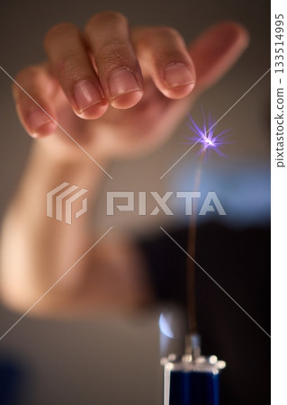 Hands manipulating metal spheres generate vibrant electrical plasma display, Laboratory scene showcasing coil discharging luminous sparks with scientific precision 133514995