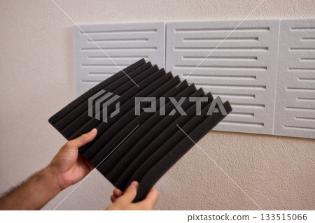Closeup of foam insulation method, Hand pressing textured acoustic foam onto wall surface, Detailed shot of fingers securing black foam panels on gray wall Comparison of different foam rubber and Closeup of foam insulation method, Hand pressing textured acoustic foam onto wall surface, Detailed shot of fingers securing black foam panels on gray wall Comparison of different foam rubber and 133515066