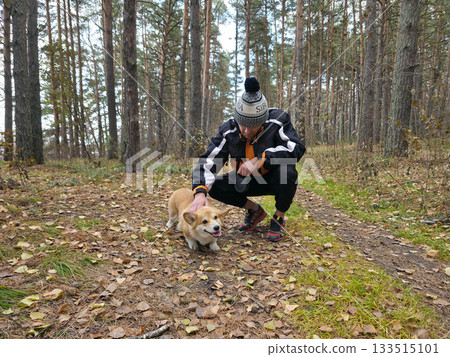 Man Playing with Corgi Dog in Autumn Forest 133515101