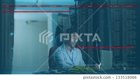 IT technician in checkered shirt configuring network gear in server room, with laptop and cables 133518066