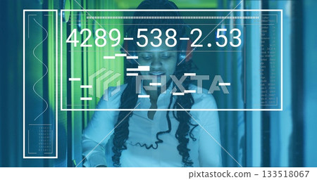 Woman wearing white shirt, headphones monitoring server racks with interface overlay at data center 133518067