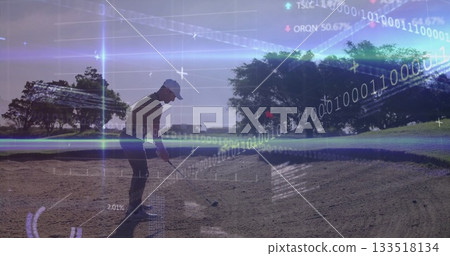 Swinging golfer in sportswear striking ball with club in golf course bunker, with digital overlays 133518134