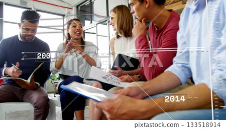 Holding notebooks and charts, team of professionals examining data overlays in office meeting room Holding notebooks and charts, team of professionals examining data overlays in office meeting room 133518914