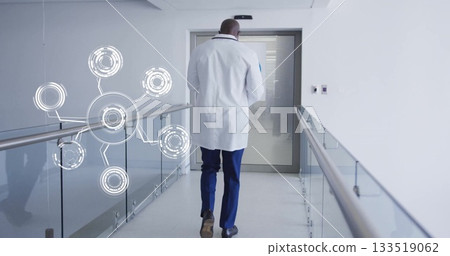 Walking doctor wearing lab coat down hospital hallway, with glass railing, digital network overlay Walking doctor wearing lab coat down hospital hallway, with glass railing, digital network overlay 133519062