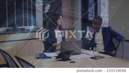 Business professionals reviewing documents at corporate conference table, with laptop and tablet 133519098