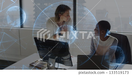 Discussing mid adult females leaning over desk in office, with laptop, data visualization overlay Discussing mid adult females leaning over desk in office, with laptop, data visualization overlay 133519173