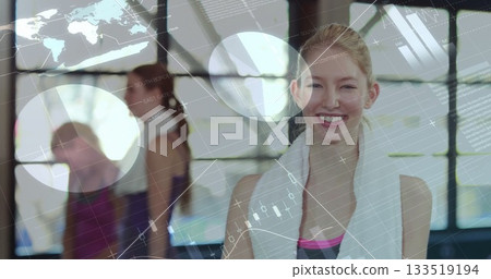 Smiling woman in sportswear holding white towel around neck in fitness studio, with digital overlay 133519194