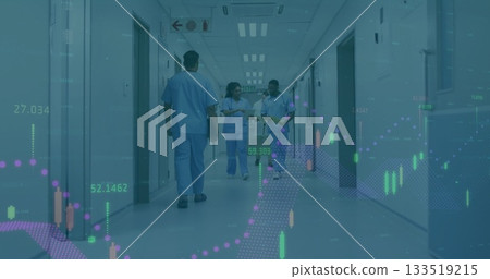 Walking scrub clad staff carrying tablet clipboard in hospital corridor, showing financial overlay 133519215