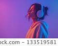 Young woman with closed eyes wearing big headphones standing on neon background with copy space 133519581