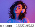 young woman with voluminous curly hair wearing big headphones on her head with closed eyes on empty day background. a woman listening to music through headphones 133519582