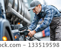 A truck driver refueling a truck at a gas station. A man inserts a fuel dispenser nozzle into the tank 133519598