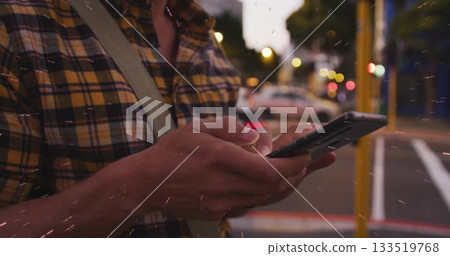 Man holding smartphone, scrolling in city street at dusk, with yellow street pole and crossbody bag Man holding smartphone, scrolling in city street at dusk, with yellow street pole and crossbody bag 133519768