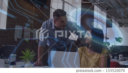 Man and woman wearing business attire discussing strategy at office desk, with laptop and hologram Man and woman wearing business attire discussing strategy at office desk, with laptop and hologram 133520070