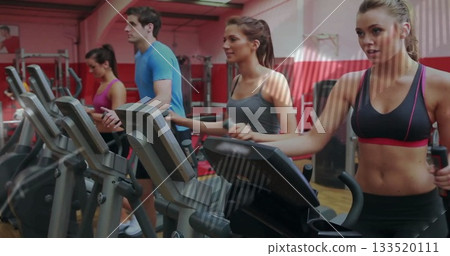 Exercising woman in red and black sportswear pedaling elliptical machine in gym, copy space Exercising woman in red and black sportswear pedaling elliptical machine in gym, copy space 133520111