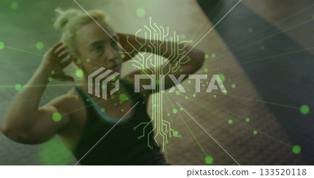 Crunching woman wearing athletic clothing on exercise mat in gym, with digital circuit graphic 133520118