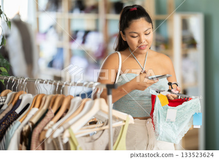 Young woman scanning qr code of panties in clothing store Young woman scanning qr code of panties in clothing store 133523624