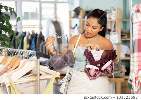 Attentive young girl choosing bra in clothing store Attentive young girl choosing bra in clothing store 133523688