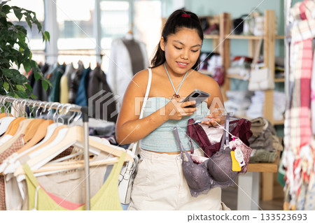 Young woman scanning qr code of underwear in store 133523693