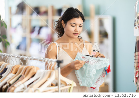 Female shopper selects panties in fashionable clothing boutique Female shopper selects panties in fashionable clothing boutique 133523710