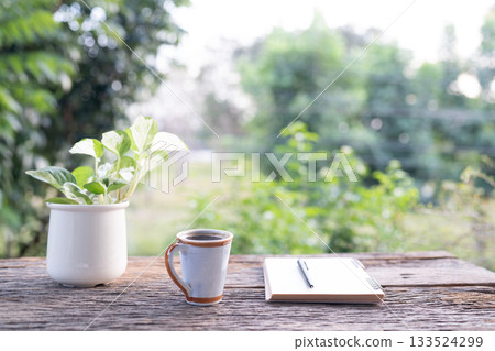 Tall coffee mug and notebook, potted plant arranged on rustic wooden table Tall coffee mug and notebook, potted plant arranged on rustic wooden table 133524299