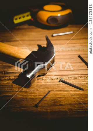 Claw hammer is resting on wooden workbench, flat design showing scattered nails and tape measure Claw hammer is resting on wooden workbench, flat design showing scattered nails and tape measure 133525318