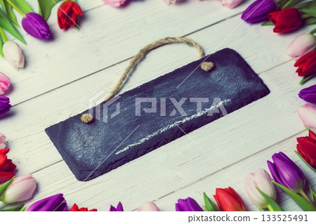 Black chalkboard sign is being shown in flat lay setup, with colorful tulip border, copy space Black chalkboard sign is being shown in flat lay setup, with colorful tulip border, copy space 133525491
