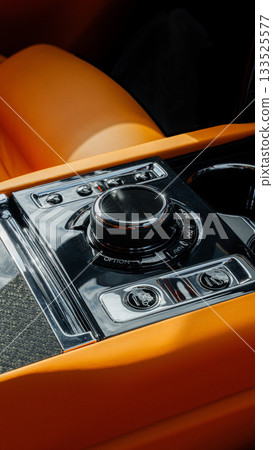 Close-up view of modern car control panel featuring sleek design and vibrant orange accents Close-up view of modern car control panel featuring sleek design and vibrant orange accents 133525577