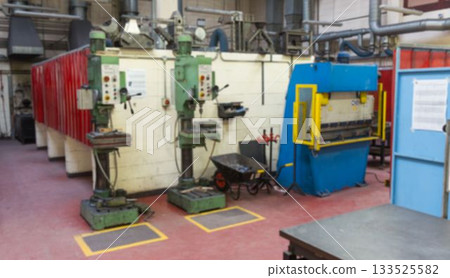 Two green drill presses are standing with blue bending brake, black barrow in flat design workshop Two green drill presses are standing with blue bending brake, black barrow in flat design workshop 133525582
