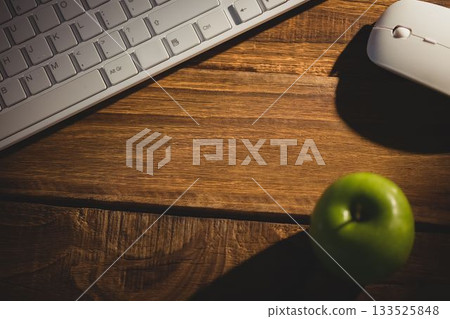 Apple by keyboard and mouse on wooden table Apple by keyboard and mouse on wooden table 133525848
