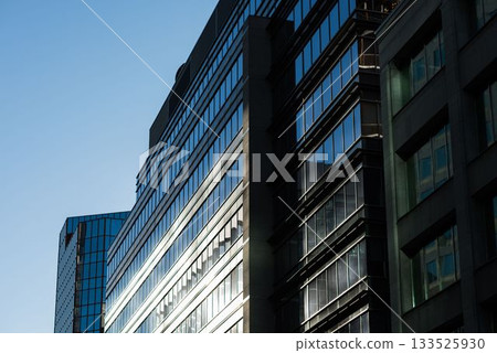 High-rise office facades are reflecting blue sky in flat design with glass and stone bands High-rise office facades are reflecting blue sky in flat design with glass and stone bands 133525930