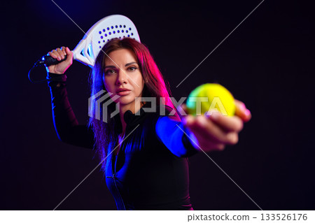 Athletic woman preparing to hit a ball with a paddle in dramatic lighting setting Athletic woman preparing to hit a ball with a paddle in dramatic lighting setting 133526176