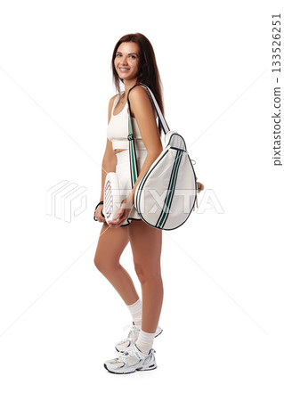 Young woman poses with a sporty bag and tennis racket in a modern setting Young woman poses with a sporty bag and tennis racket in a modern setting 133526251