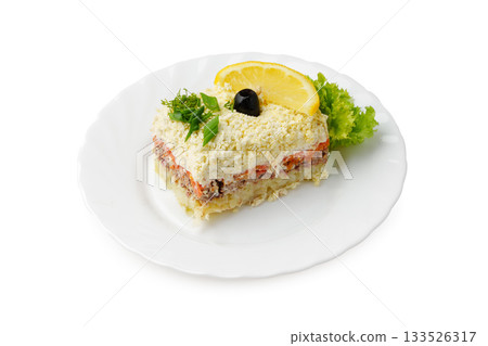 Savory layered fish dish with lemon and greens served on a plate 133526317