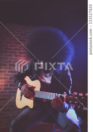 Man playing guitar in nightclub during concert 133527820