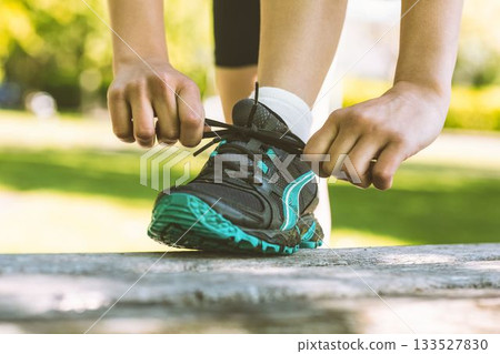 Low section of woman tying shoelace Low section of woman tying shoelace 133527830