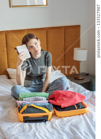 Woman dreaming of travel while packing suitcase for vacation 133527987