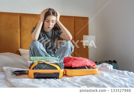 Woman feeling stressed packing suitcase for trip 133527988