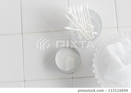 Moisturizing cream, cotton swabs and cotton pads arranged on white tiles 133528899