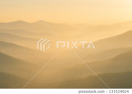 A serene landscape of misty mountains enveloped in morning light 133529024