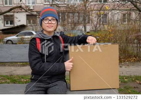 teenager sits on a bench showing a thumbs up with a box 133529272