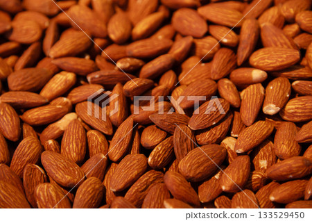 Delicious roasted almonds with spices are sold in large quantities at a vegetable market. Close-up. Almond background. 133529450