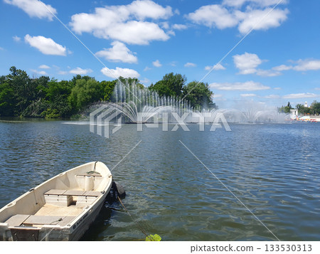 A boat on a river against the backdrop of an elegant fountain is an idyllic summer landscape filled with peace 133530313