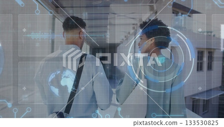 Walking colleagues carrying bag and exploring glass windowed corridor, with holographic interface 133530825