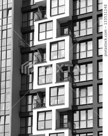 Close-up view of modern apartment facade with geometric balcony design and large glass windows. 133531148