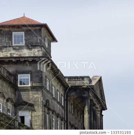Building historic stone facade with columns and tiled roof. Classical architecture in European city 133531193